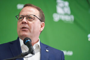 Photo of Mike Schreiner in front of a green background