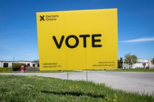 A yellow VOTE sign on a lawn
