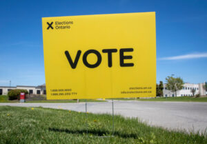 A yellow Ontario VOTE election sign on a lawn