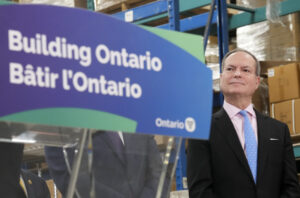 Ontario Finance Minister Peter Bethlenfalvy listens to Ontario Premier Doug Ford speak after touring the Oakville Stamping and Bending Limited in advance of the presentation of the Ontario Budget in March 2023